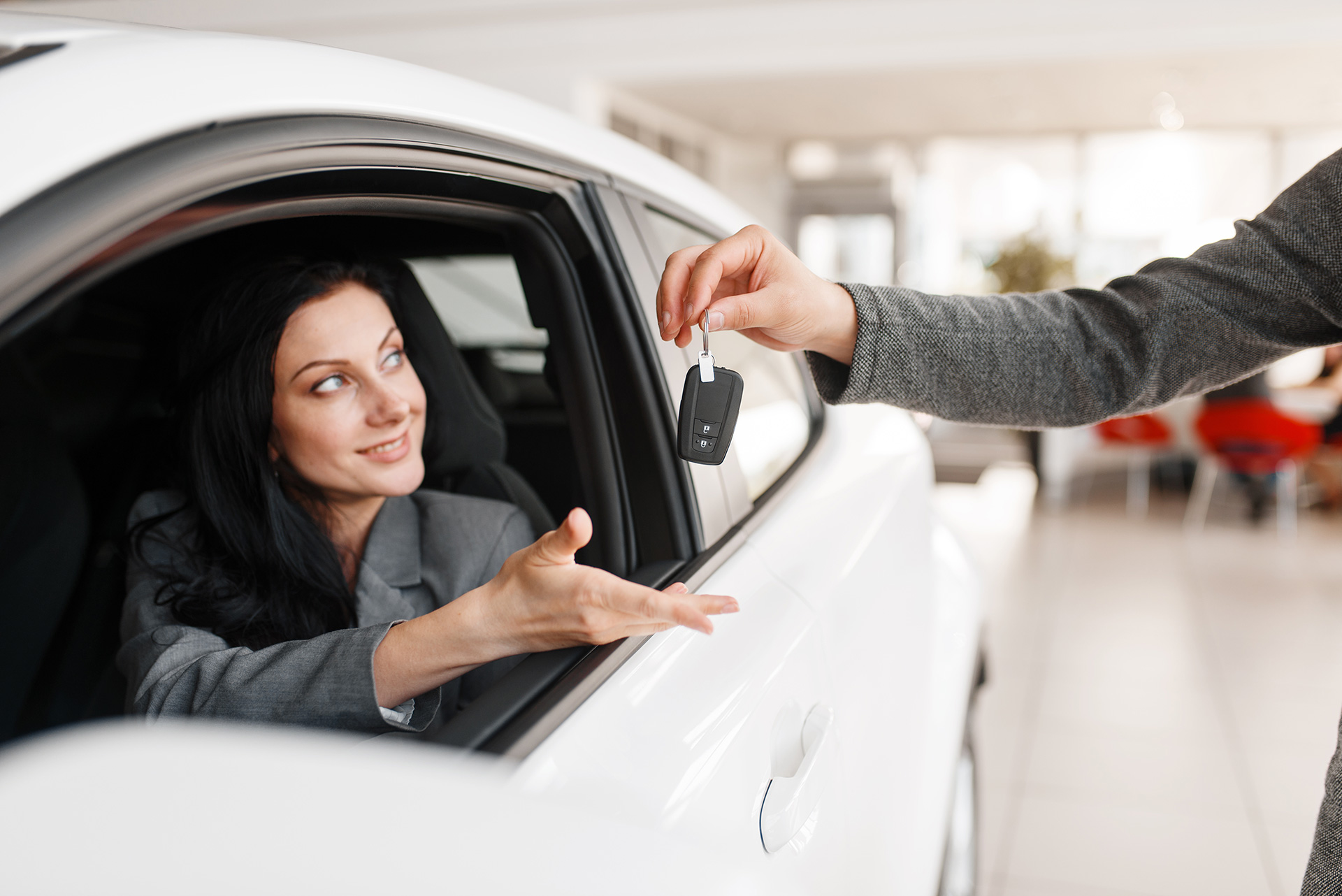 happy-woman-takes-the-key-to-new-car-in-showroom-2024-11-30-03-20-20-utc